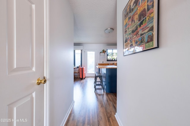 hall featuring dark wood-type flooring and a textured ceiling