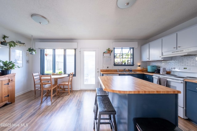 kitchen featuring butcher block countertops, white cabinetry, a kitchen island, white electric range oven, and a kitchen bar