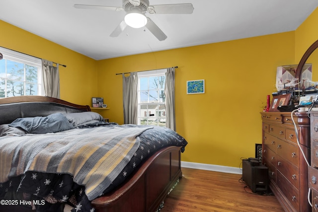 bedroom featuring ceiling fan, hardwood / wood-style floors, and multiple windows