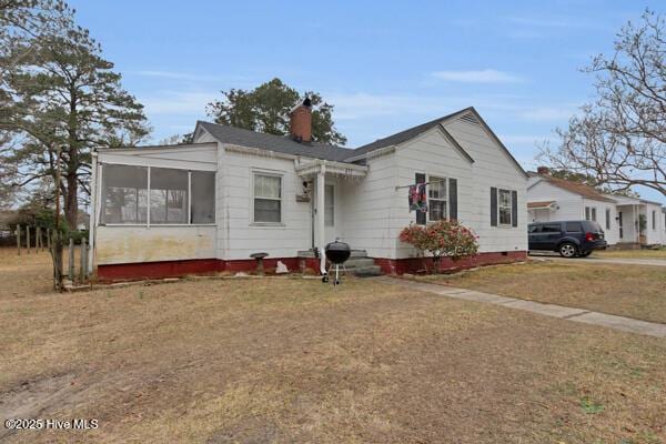 view of front of home featuring a front lawn and a sunroom