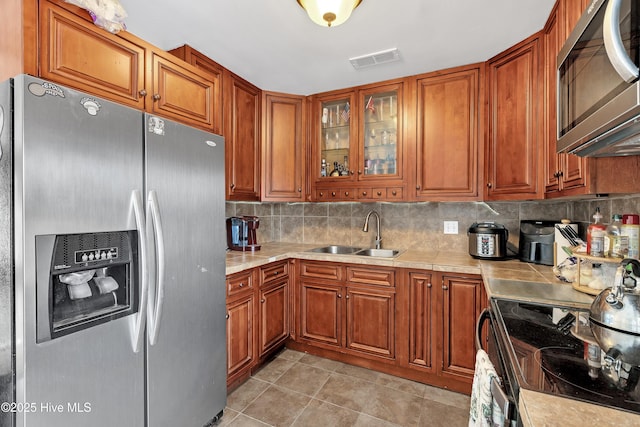 kitchen with light tile patterned floors, appliances with stainless steel finishes, sink, and backsplash