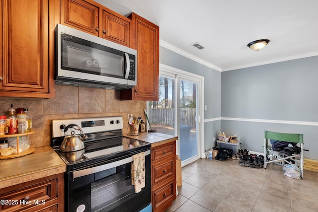 kitchen featuring tile countertops, decorative backsplash, ornamental molding, light tile patterned floors, and stainless steel appliances