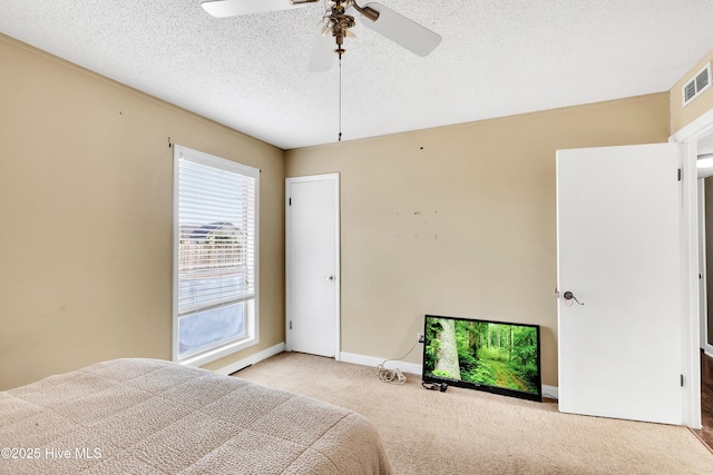 unfurnished bedroom with ceiling fan, light colored carpet, and a textured ceiling