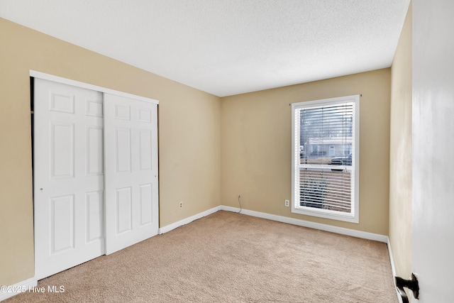 unfurnished bedroom featuring light colored carpet, a closet, and a textured ceiling