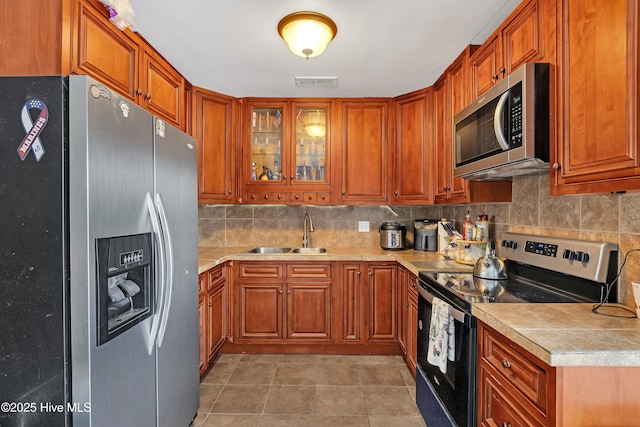 kitchen featuring tasteful backsplash, sink, light tile patterned floors, and appliances with stainless steel finishes