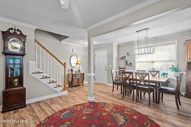 dining room featuring light wood-type flooring, crown molding, and a textured ceiling