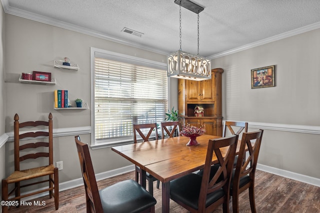 dining space featuring dark wood-type flooring, ornamental molding, and a textured ceiling