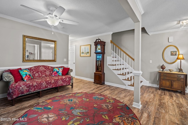 living room with ceiling fan, crown molding, wood-type flooring, and a textured ceiling