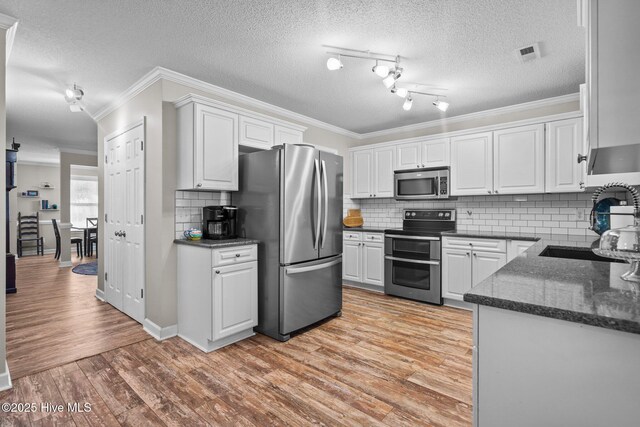 kitchen with sink, stainless steel appliances, white cabinetry, and light hardwood / wood-style floors