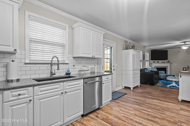 kitchen with sink, white cabinets, ornamental molding, stainless steel dishwasher, and light wood-type flooring