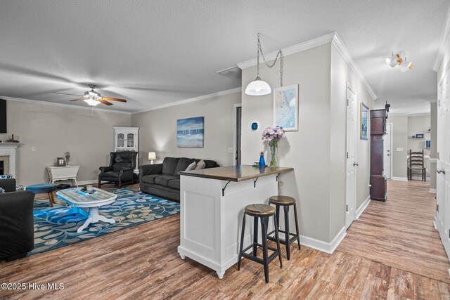 kitchen with a textured ceiling, crown molding, kitchen peninsula, hardwood / wood-style flooring, and a breakfast bar area