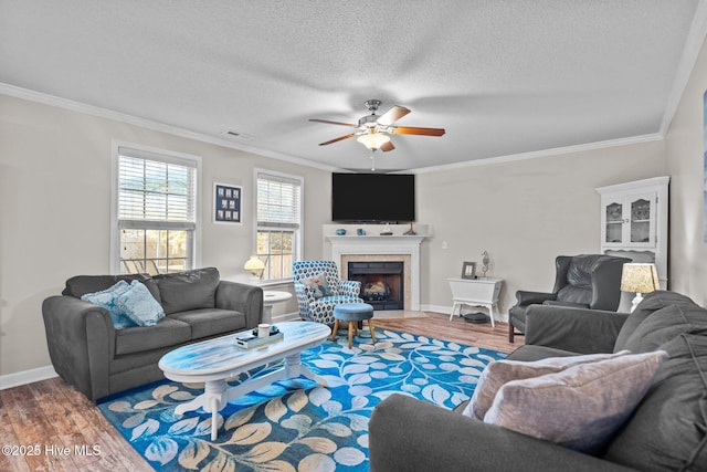 living room featuring crown molding, wood-type flooring, and a tile fireplace