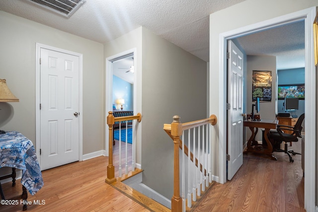 corridor with light hardwood / wood-style floors and a textured ceiling