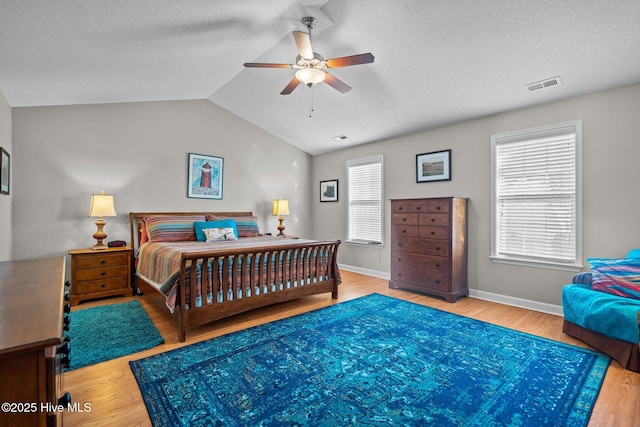 bedroom with a textured ceiling, vaulted ceiling, and hardwood / wood-style floors