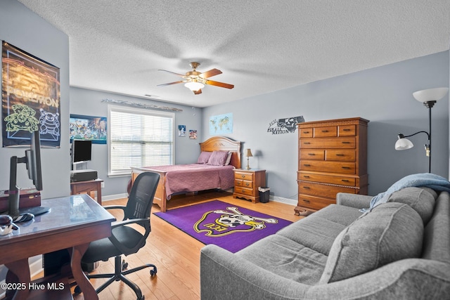 bedroom featuring ceiling fan, hardwood / wood-style floors, and a textured ceiling