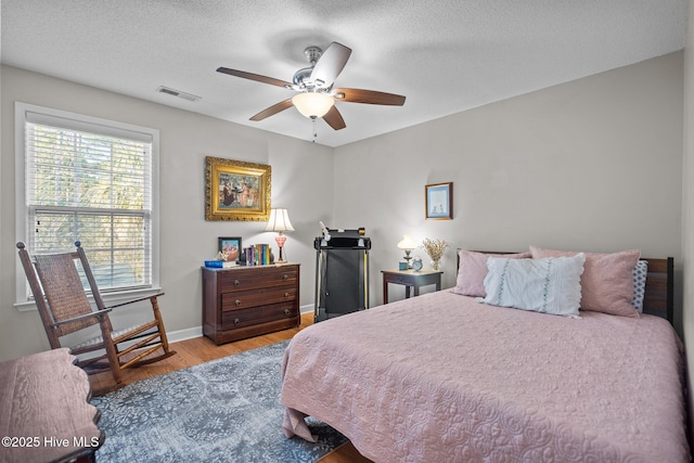 bedroom with ceiling fan, a textured ceiling, and light wood-type flooring