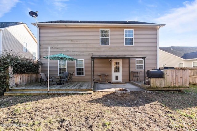 rear view of house with a wooden deck and a fire pit