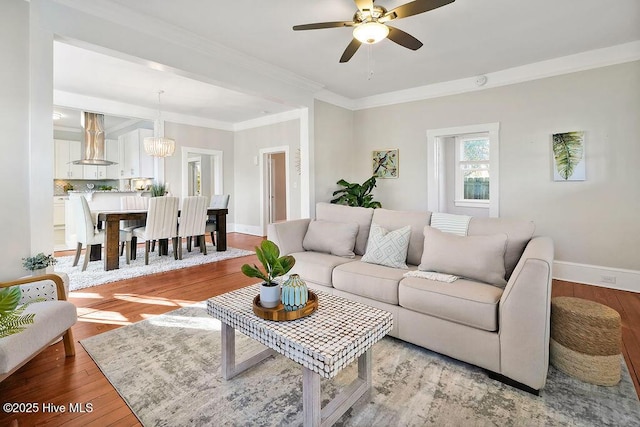 living room with crown molding, ceiling fan with notable chandelier, and light wood-type flooring