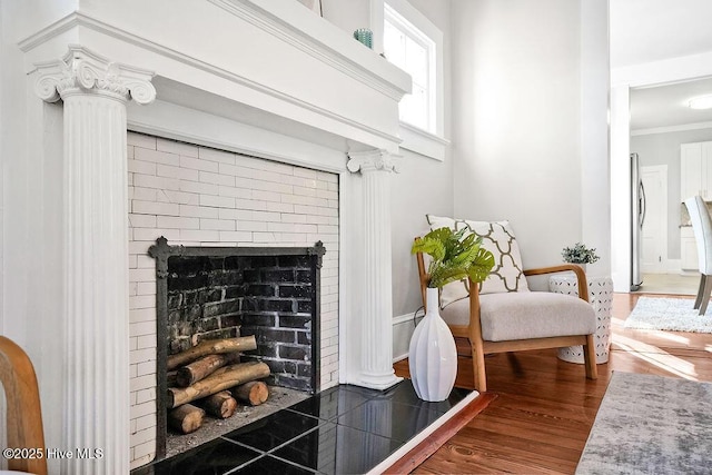 interior details with wood-type flooring, a brick fireplace, stainless steel fridge, and crown molding