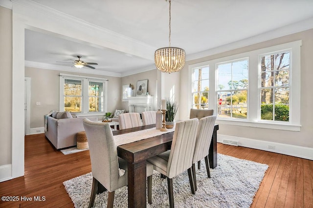 dining room featuring dark wood-type flooring, plenty of natural light, ornamental molding, and ceiling fan with notable chandelier