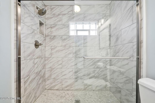 bathroom featuring a shower with shower door and toilet