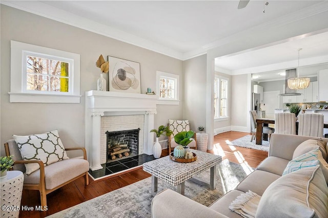 living room with crown molding, a notable chandelier, a tile fireplace, and hardwood / wood-style flooring