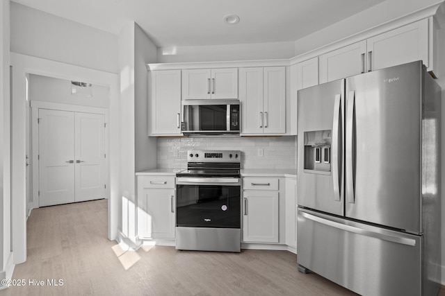 kitchen featuring backsplash, stainless steel appliances, light hardwood / wood-style floors, and white cabinets