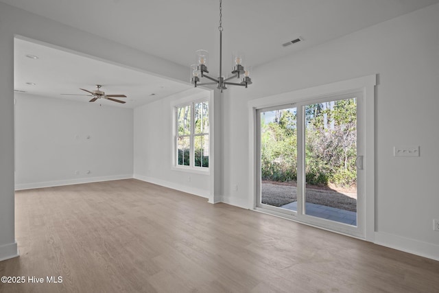 unfurnished living room featuring ceiling fan with notable chandelier and wood-type flooring