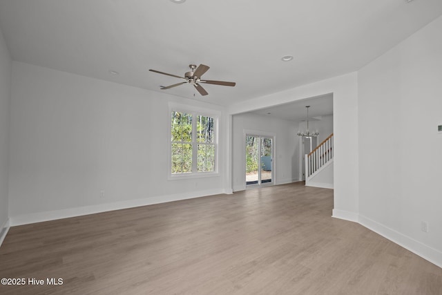 unfurnished living room featuring wood-type flooring and ceiling fan with notable chandelier