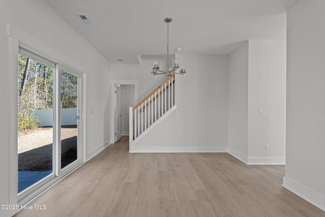 unfurnished room featuring an inviting chandelier and light wood-type flooring