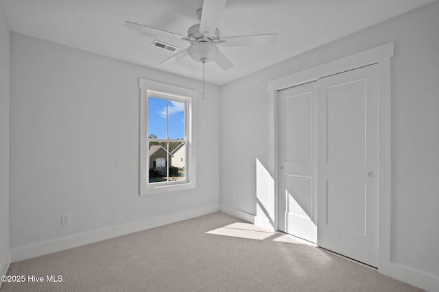 unfurnished bedroom featuring light colored carpet, ceiling fan, and a closet