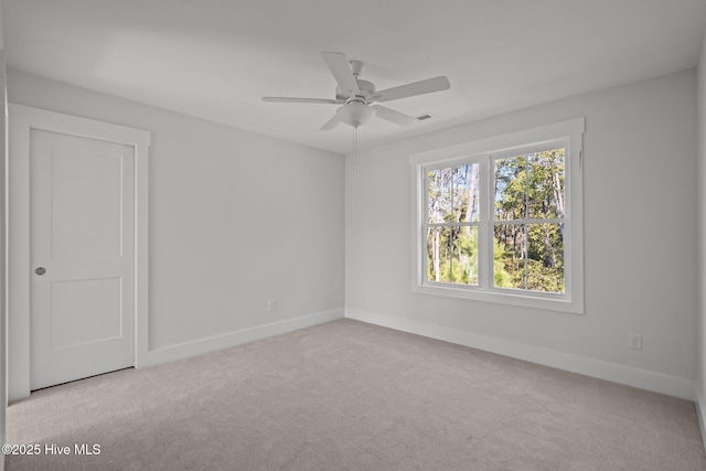 spare room featuring light carpet and ceiling fan