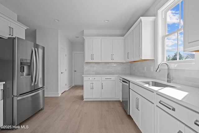 kitchen with light wood-type flooring, appliances with stainless steel finishes, sink, and white cabinets