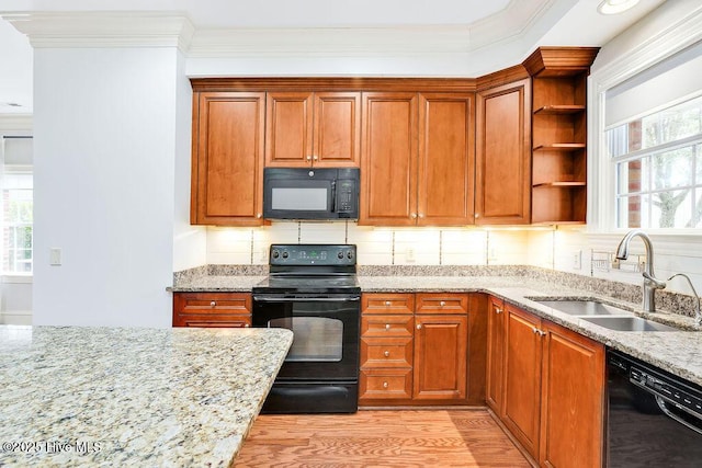 kitchen with sink, black appliances, ornamental molding, light stone countertops, and light wood-type flooring