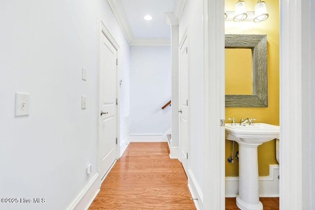 hallway with sink, wood-type flooring, and ornamental molding