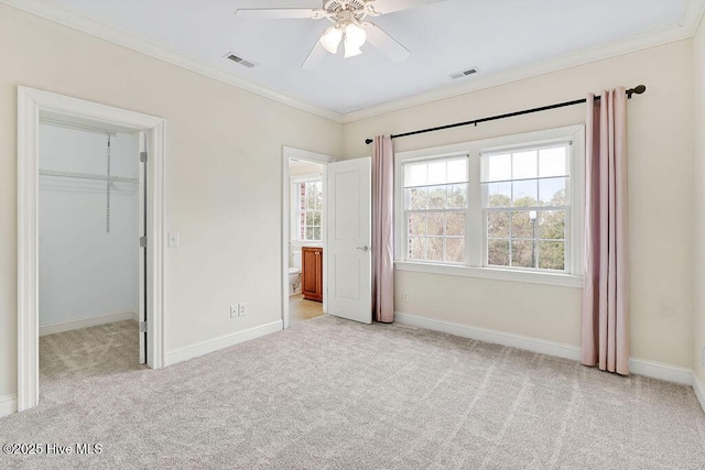 unfurnished bedroom featuring crown molding, a spacious closet, and light colored carpet