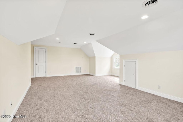 additional living space featuring light carpet and vaulted ceiling