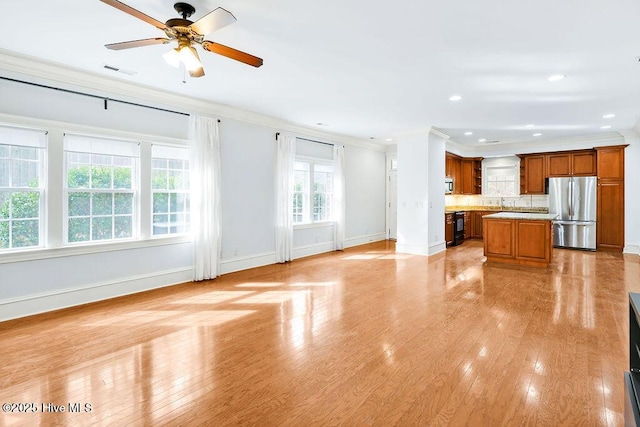 unfurnished living room featuring crown molding, ceiling fan, and light hardwood / wood-style floors