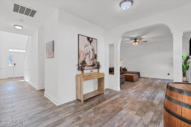 hall with hardwood / wood-style floors and ornate columns