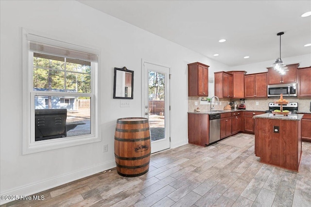 kitchen featuring a kitchen island, appliances with stainless steel finishes, decorative light fixtures, sink, and decorative backsplash