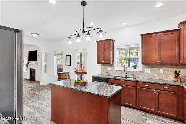 kitchen featuring stone counters, stainless steel dishwasher, a center island, and sink