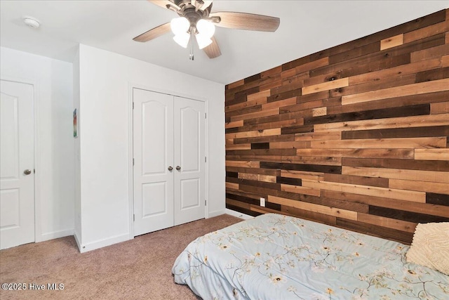 carpeted bedroom featuring a closet, ceiling fan, and wood walls