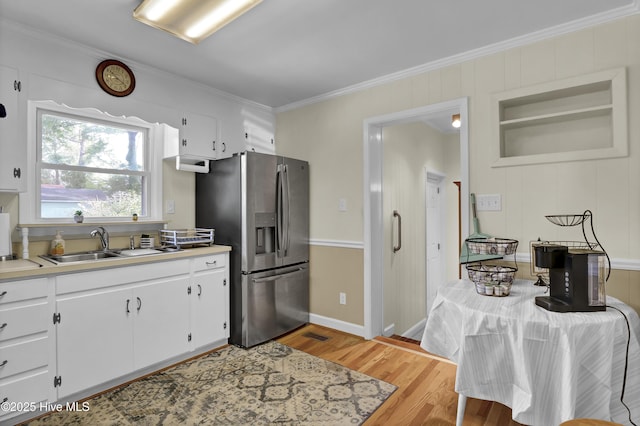 kitchen featuring sink, white cabinets, ornamental molding, light hardwood / wood-style floors, and stainless steel refrigerator with ice dispenser