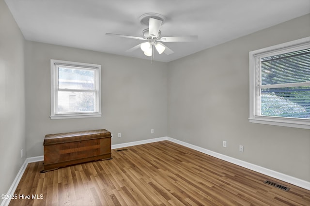 empty room featuring plenty of natural light, ceiling fan, and light wood-type flooring