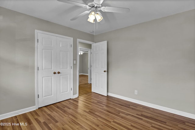 unfurnished bedroom featuring ceiling fan, wood-type flooring, and a closet