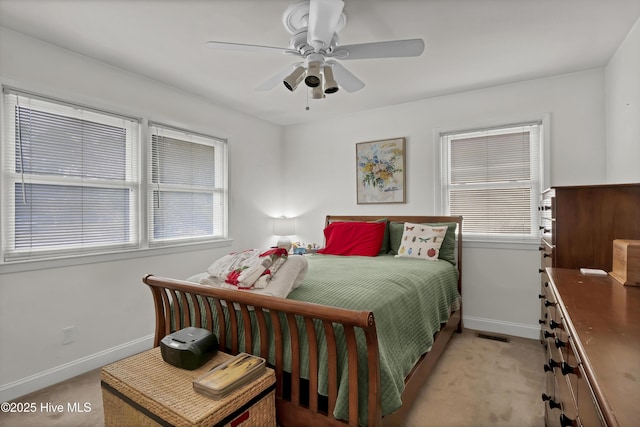 bedroom featuring ceiling fan, light colored carpet, and multiple windows