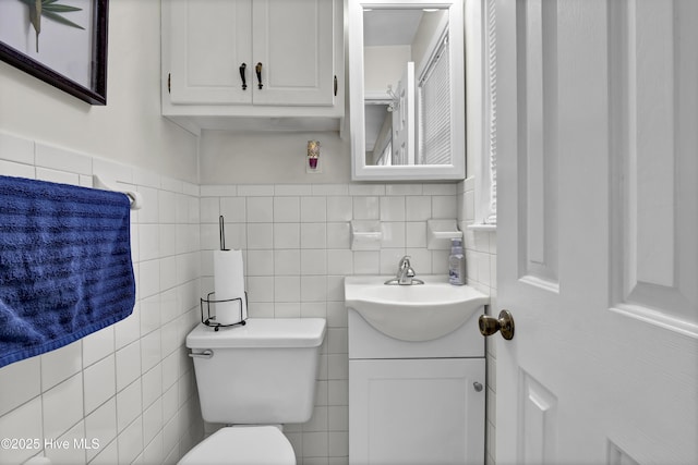 bathroom featuring vanity, tile walls, and toilet