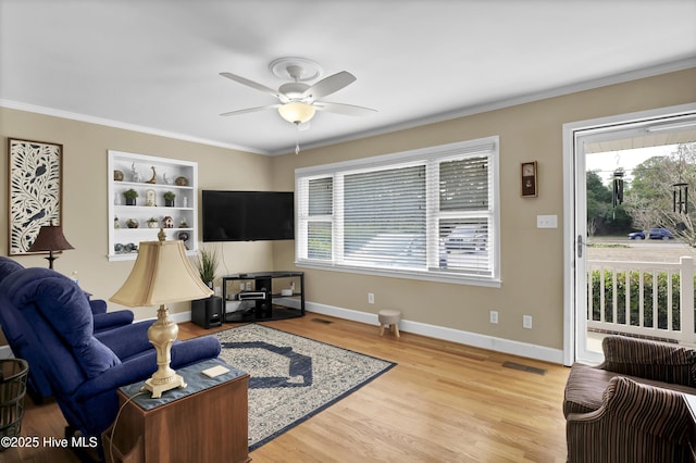 living room with light hardwood / wood-style flooring, crown molding, a wealth of natural light, and ceiling fan