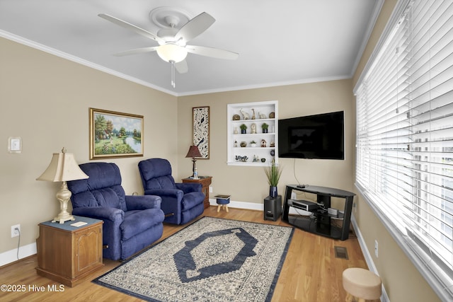 living room with crown molding, a wealth of natural light, and light wood-type flooring