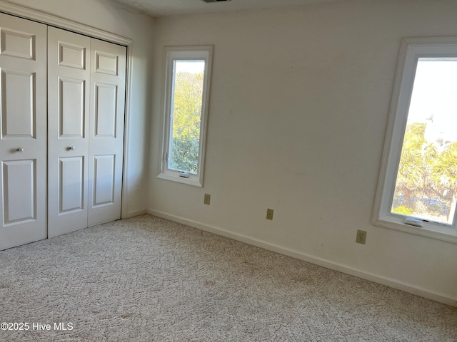 unfurnished bedroom with a closet and light carpet